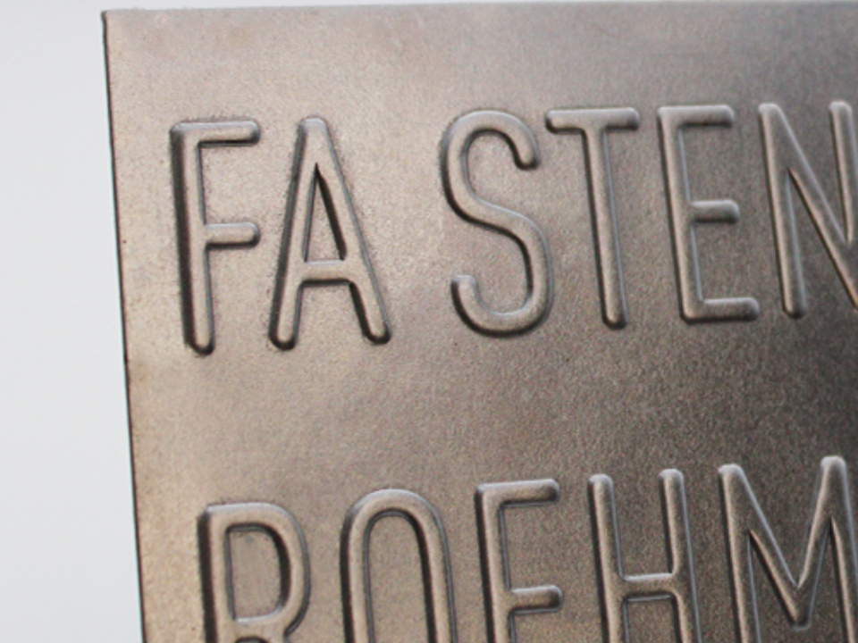 Nahaufnahme eines Metallschilds mit geprägter Beschriftung