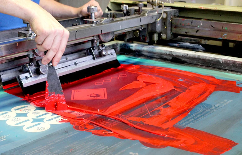 Detailaufnahme der Farbauftrag-Maschine beim Siebdruck von Industrieschildern